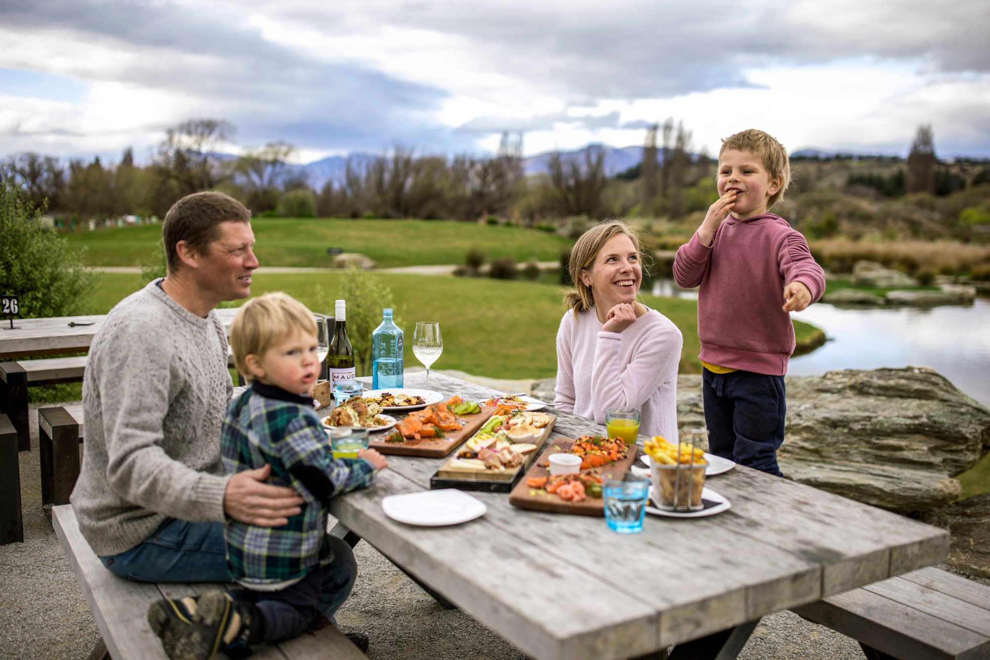 family eating at a picnic table outside grazing platter