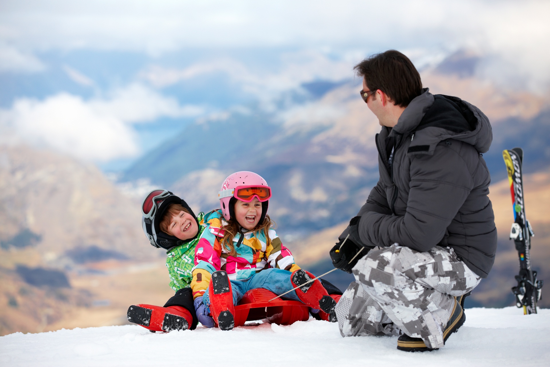 Father and two children on ski mountain playing